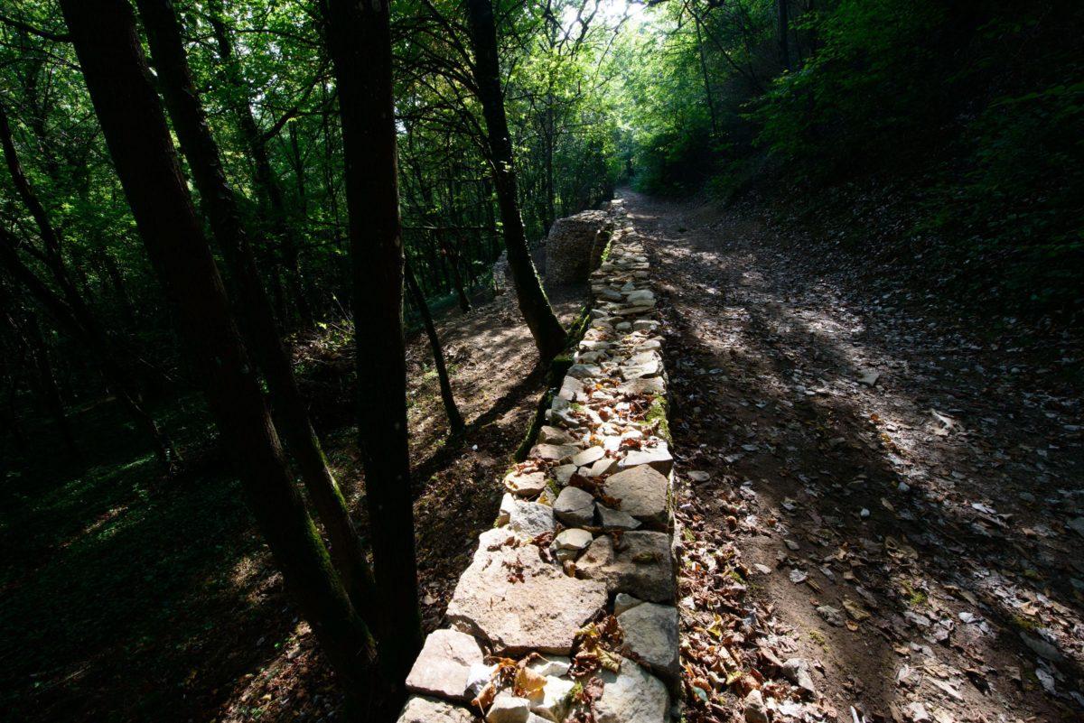 Le chemin des Pierres Blanches, avec visible en arrière plan la caborne adossée au mur de soutènement du chemin.